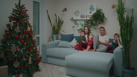 family bonding at christmas. together on a sofa and watching tv at home during christmas holidays. high quality 4k footage