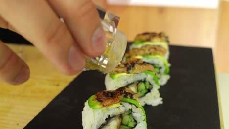 chef de sushi espolvoreando pan de oro en rollos de sushi