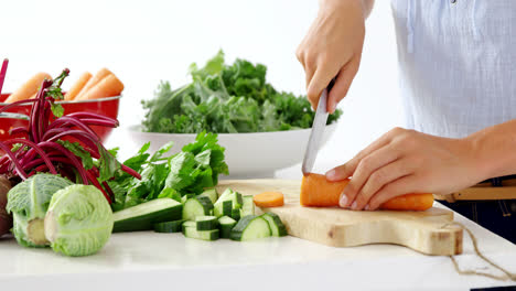 sección media de una mujer cortando verduras en una tabla de cortar