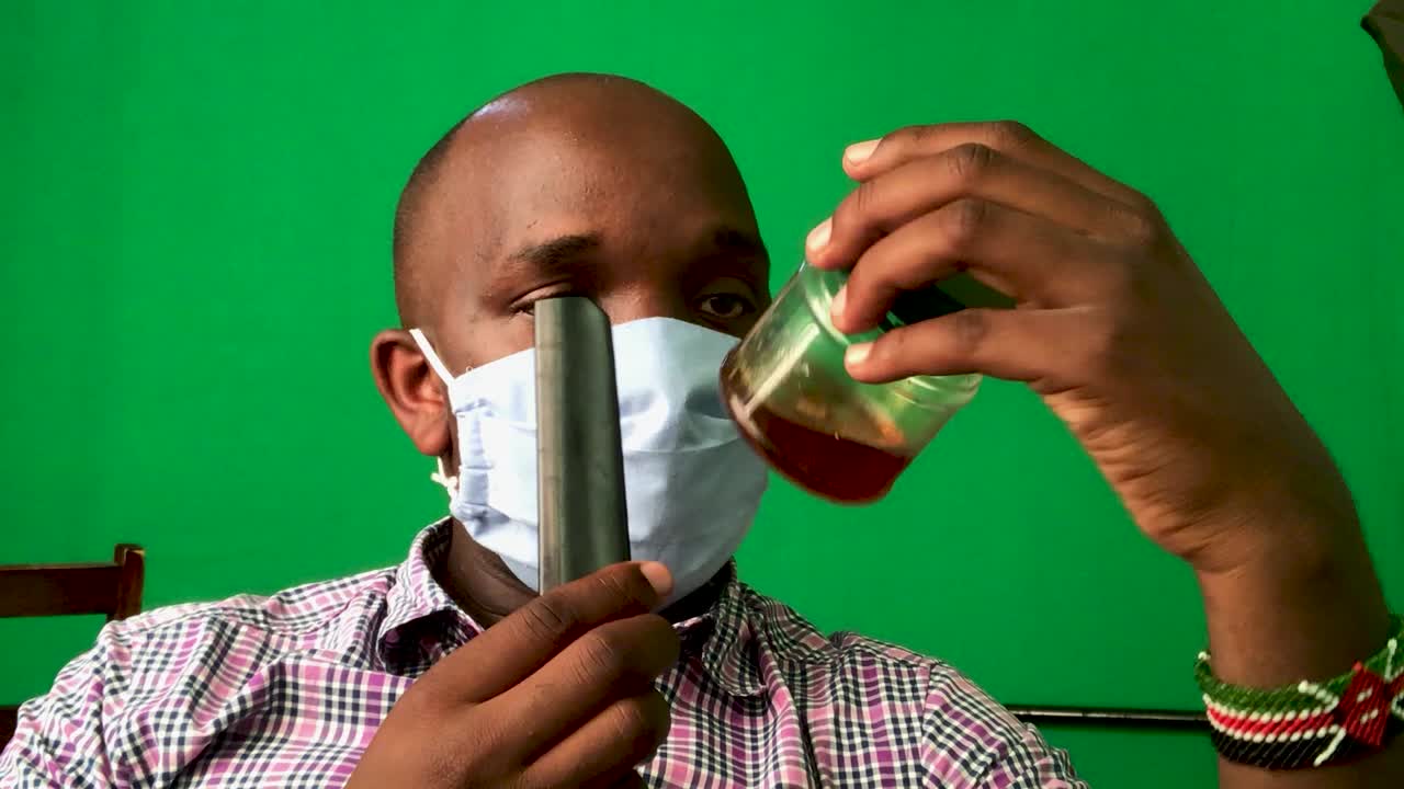 African man removing face mask and drinking healthy honey against coronavirus influenza