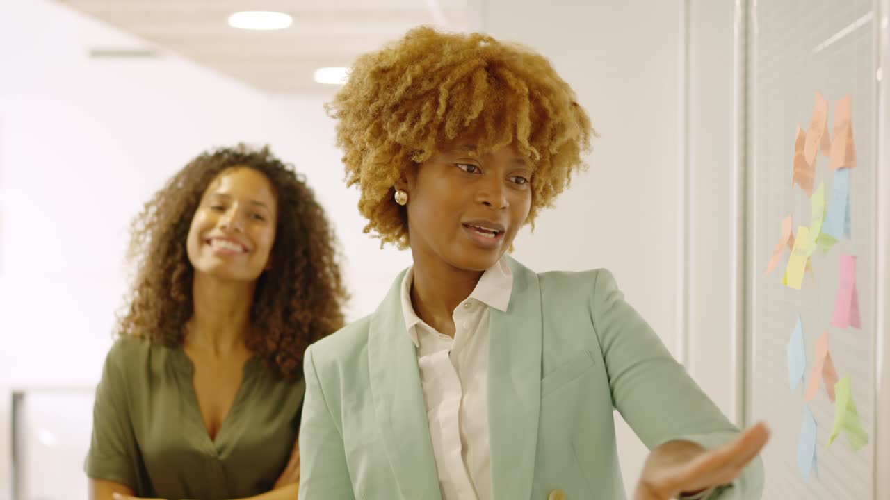 African woman pointing a post-it presenting ideas in a meeting
