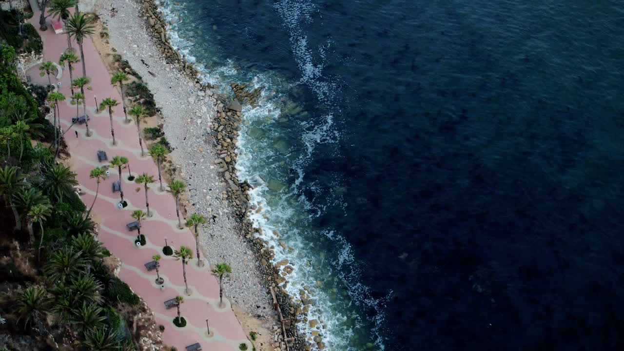vista aérea de pájaro de arriba hacia abajo de las olas rompiendo en una playa rocosa del sur de california