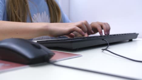 El-Primer-Plano-De-Una-Joven-Usando-Una-Computadora-En-La-Escuela-Desenfoque-De-La-Mano-En-El-Mouse-Al-Teclado