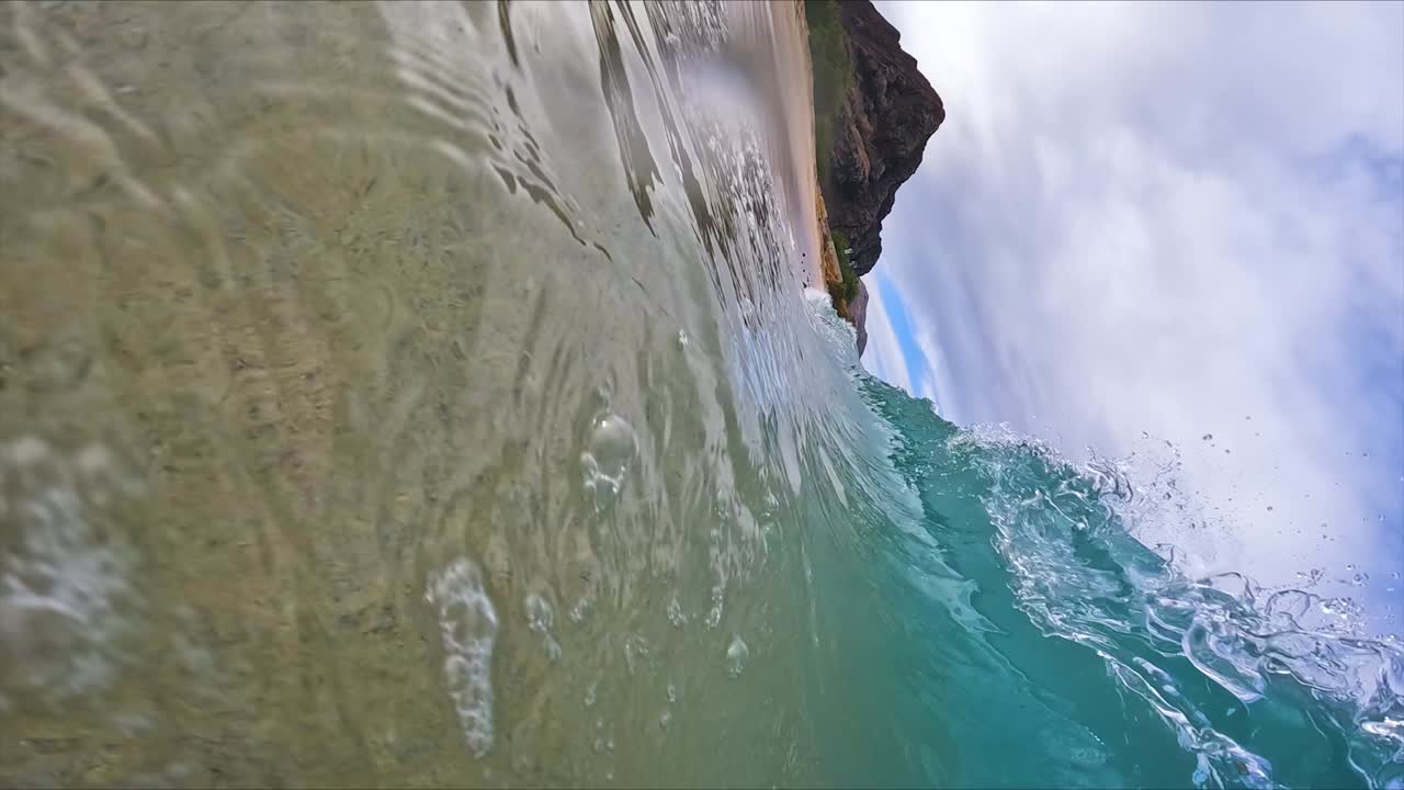 Onde oceaniche che si infrangono su una spiaggia sabbiosa alle Hawaii, verticale