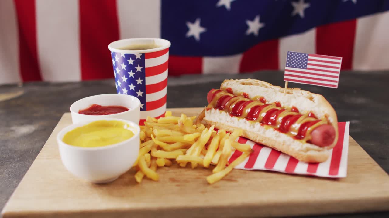 Video di hot dog con senape, ketchup e patatine sopra la bandiera degli Stati Uniti su una superficie di legno