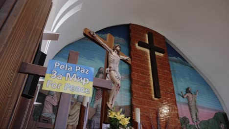 crucifix with ukrainian peace flag displayed alongside religious art and flowers in the church