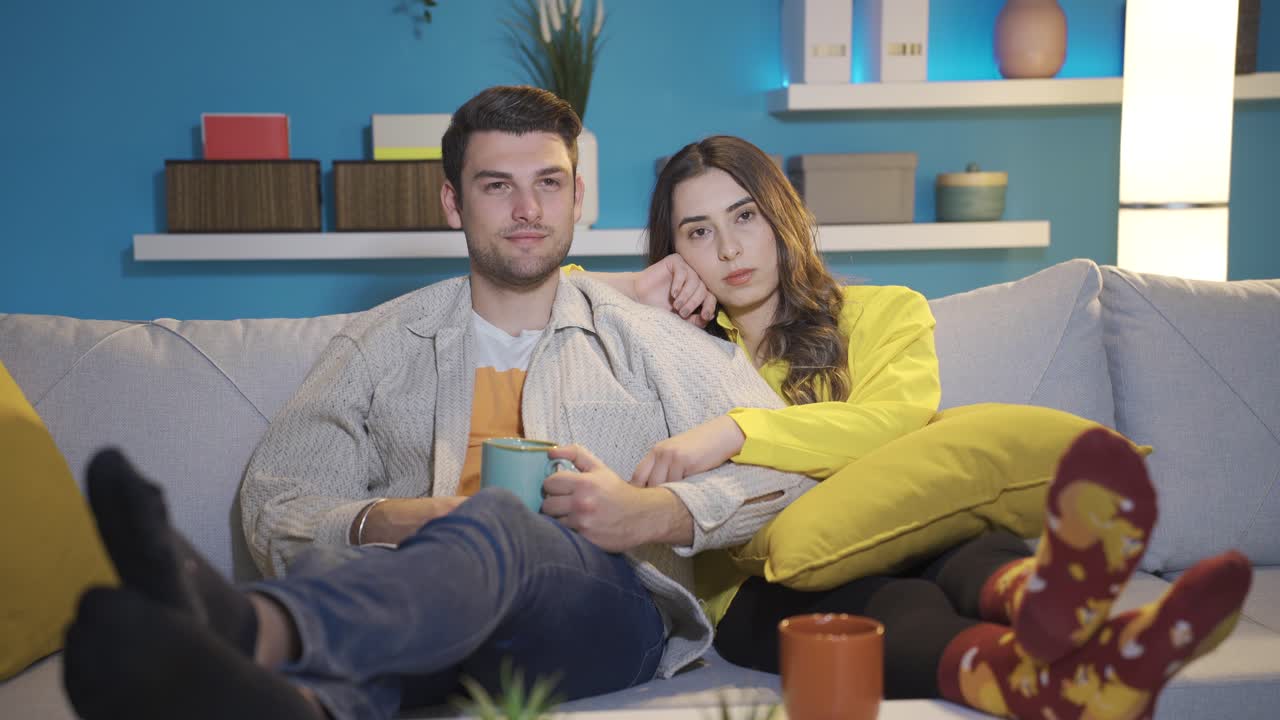 Coppia felice che riposa e si rilassa sul divano guardando un film drammatico ed emozionante in TV. Coppia romantica