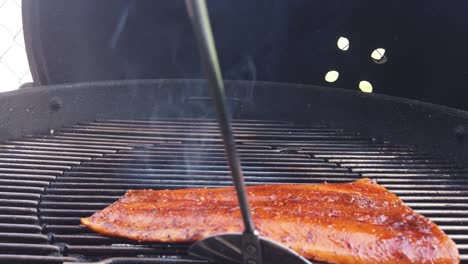 volteando un filete de salmón en la parrilla de la barbacoa - cámara lenta aislada