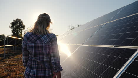 una mujer camina a lo largo de los paneles solares de una pequeña planta de energía solar doméstica