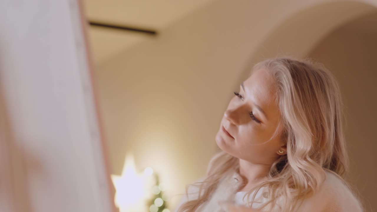 금발의 여성 화가 가운 방에서 캔버스를 그린다