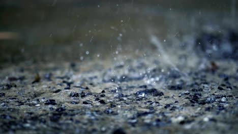 movimiento lento de primer plano de la gota de lluvia cayendo en la calle hormigón, aspecto de película vintage