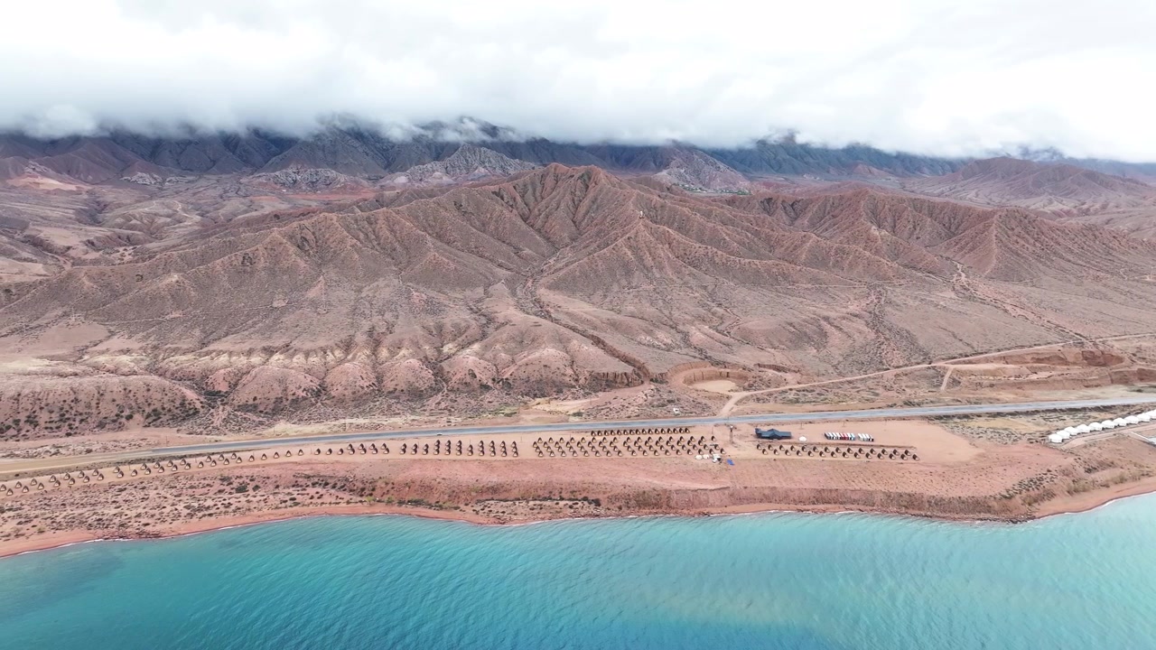 Epica vista aerea della costa del Lago Issyk-Kul con capanne e montagne aspre, paesaggio del Kirghizistan.