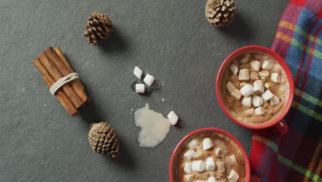 Video-of-coffee-with-marshmallows,-pine-cones-and-cinnamon-on-grey-background