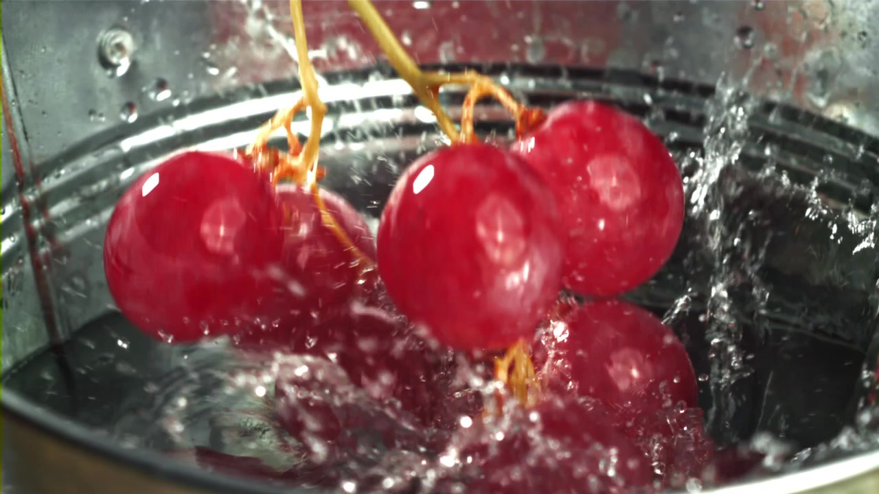 Uva rossa fresca che schizza nell'acqua al rallentatore