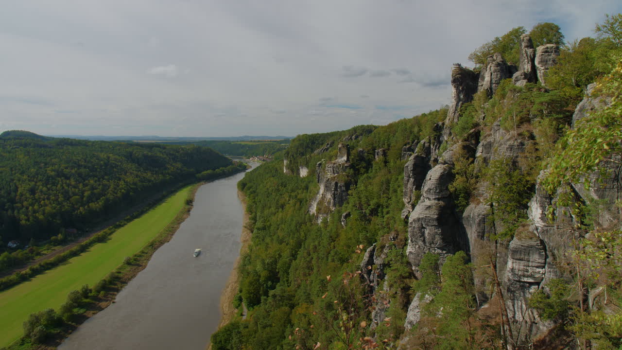 Elbsandsteingebirge Sachsen Elbe sandstone formations rising above dense green forests Mountains, blue sky with scattered clouds, showcasing the region’s natural beauty and rugged Terrain