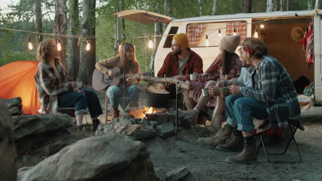 friends singing to guitar by campfire