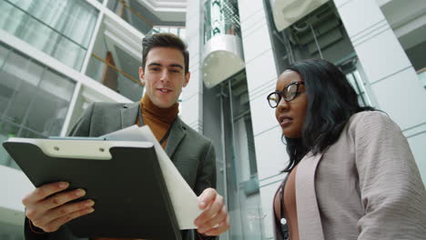 Multiethnic-Business-Partners-Discussing-Papers-in-Office-Center