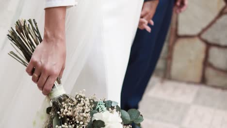 Novia-Con-Vestido-Blanco-Llevando-Ramo-De-Flores-Sosteniendo-La-Mano-De-Su-Novio-En-El-Día-De-La-Boda