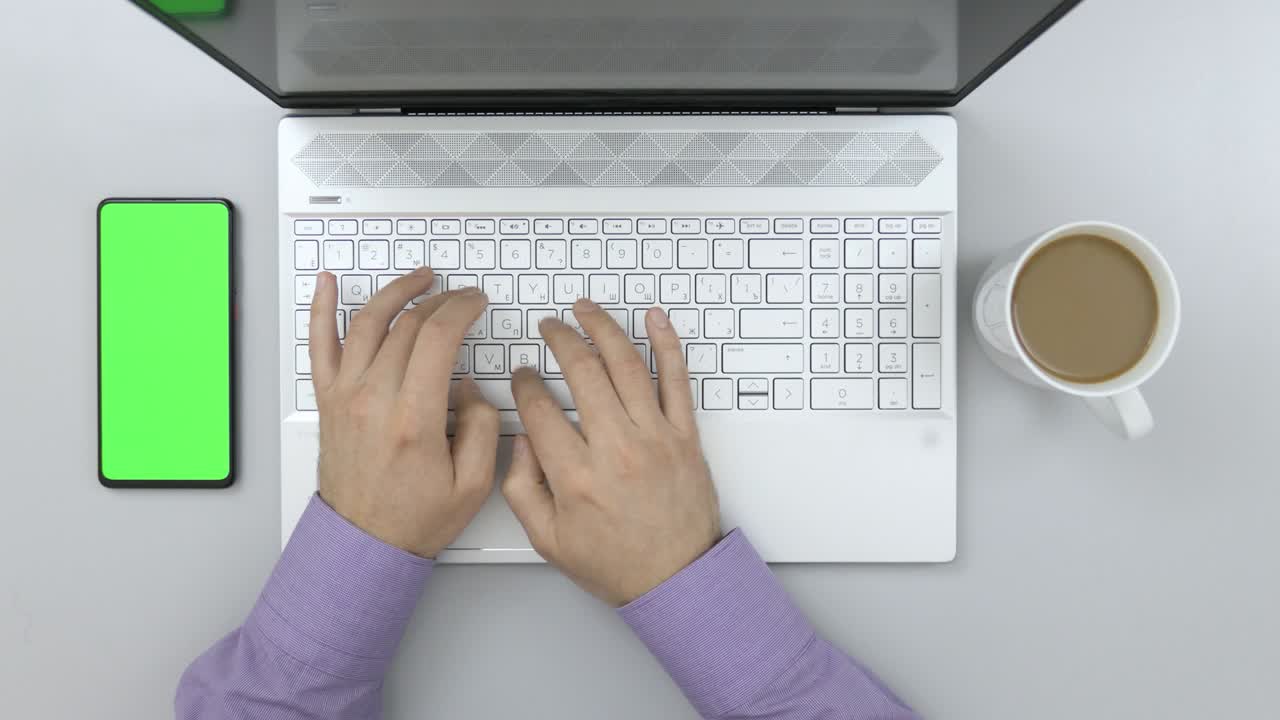 hombre de negocios escribiendo en una computadora portátil en el escritorio. pantalla verde teléfono inteligente. estudiante estudiando. vista superior mesa de trabajo diseñador creativo. freelance trabajando en computadora de escritorio. taza de café. mesa de oficina espacio de trabajo.