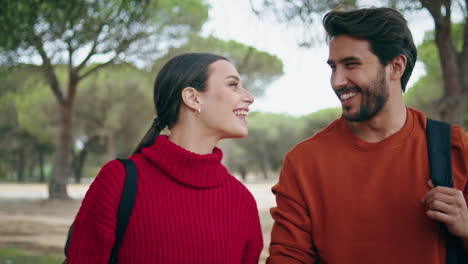 Happy-couple-enjoy-walk-in-autumn-forest-close-up.-Hikers-talking-strolling-park