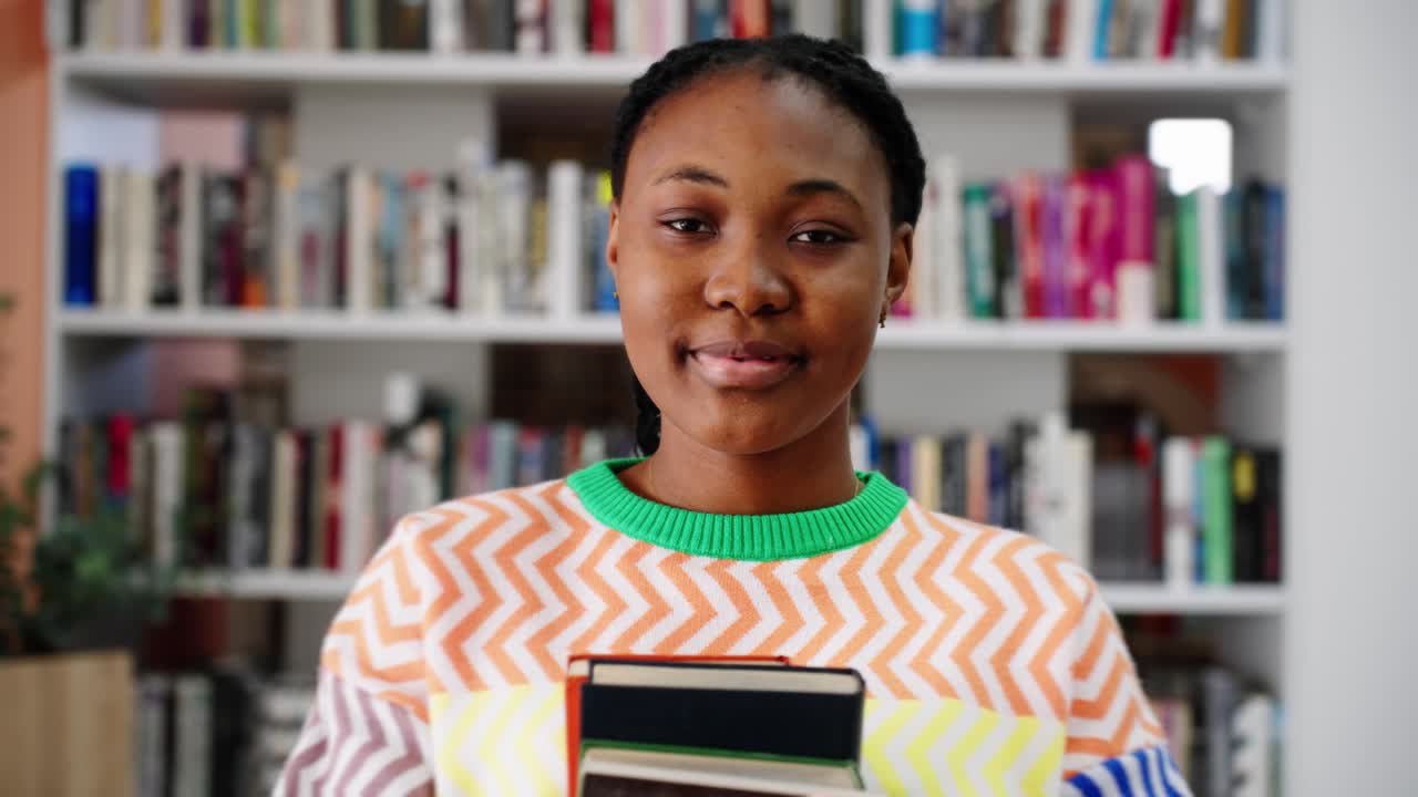 Young African American Woman Holding Books in a Library