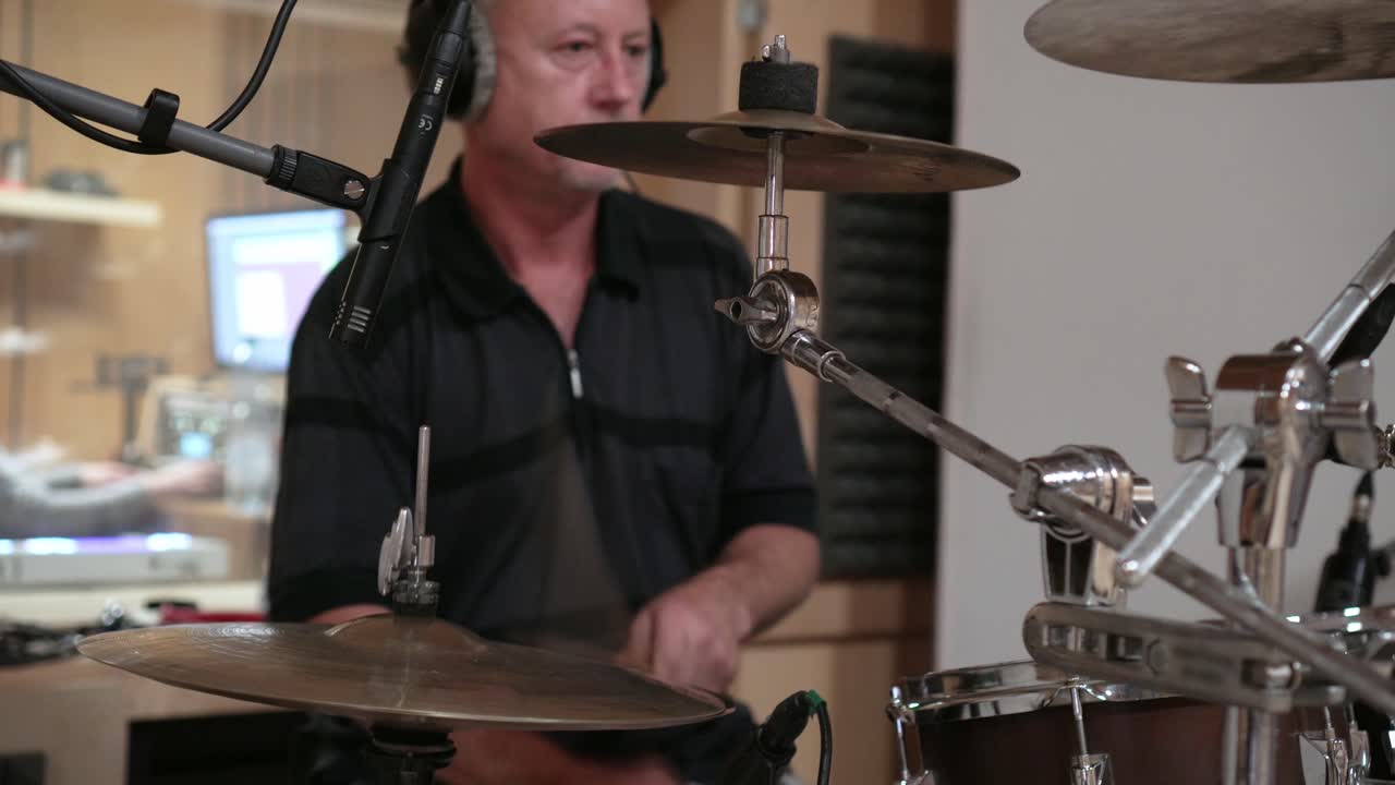 Man playing hi-hat and snare drum in a studio, front view closeup
