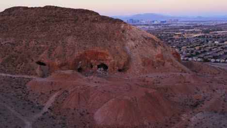 Aerial-view-of-Las-Vegas-Nevada-as-seen-in-the-distance-with-desolate-red-mountains-in-the-foreground