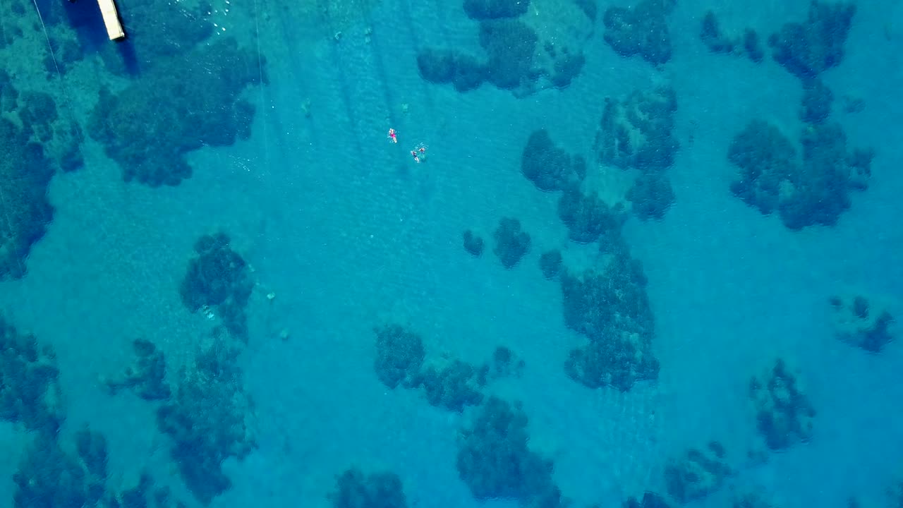 Drone rising shot of the swimming people in the beautiful turquoise bay.