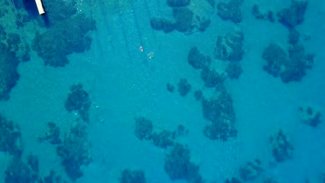 drone rising shot of the swimming people in the beautiful turquoise bay.
