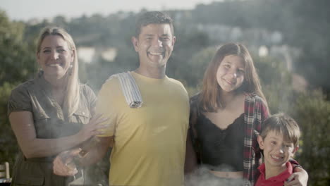 retrato de una familia feliz de pie en la parrilla de barbacoa y sonriendo