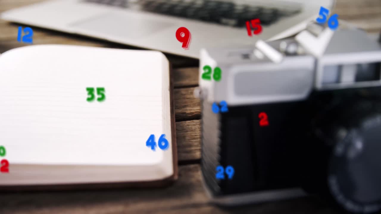 Animation of numbers changing over close up of desk with camera and laptop