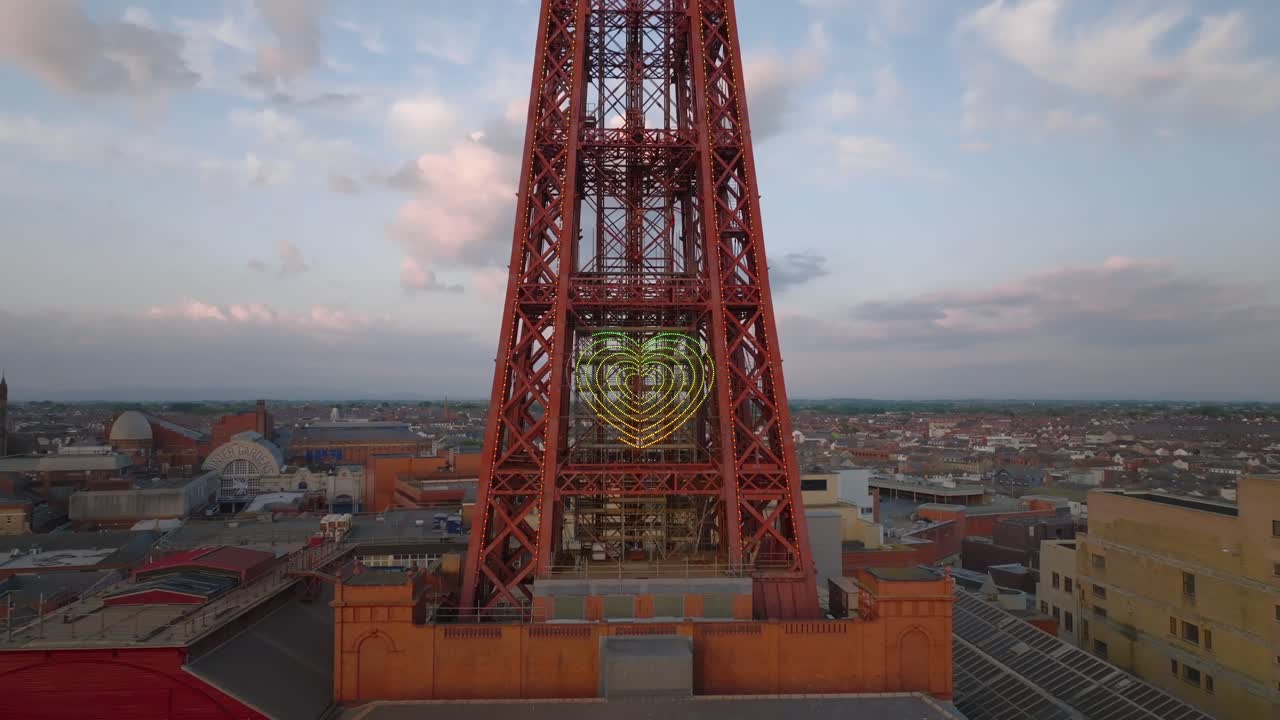 Pulling away from Blackpool tower to reveal full structure with town behind. Golden hour. Lancashire, UK.