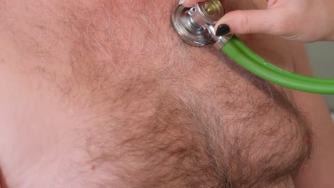 a caring female doctor examines the heart rate of a mature patient using a stethoscope during an examination in the hospital. a general practitioner uses a stethoscope while listening to an elderly man’s heartbeat