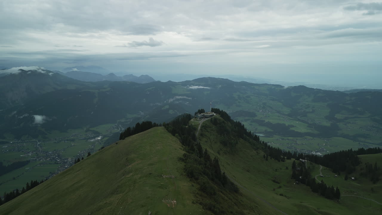 Drone aerial view of a mountain ridge in the Bregenz Forest in Austria. In the foreground is a mountain station of a cable car. Lake Constance is easily recognizable in the bad weather.