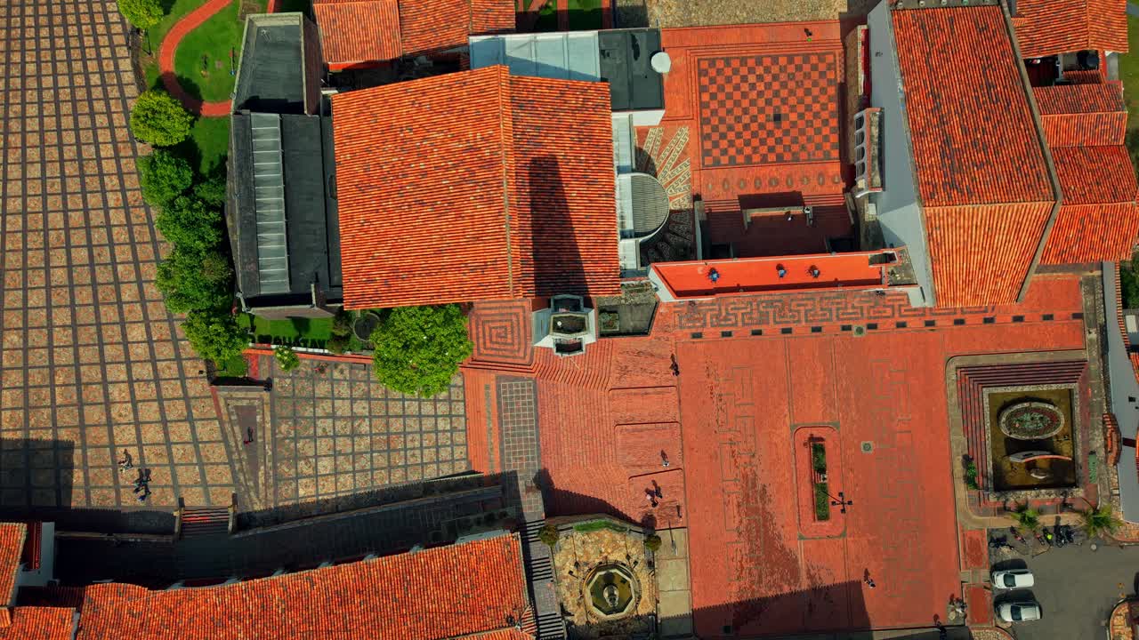 Aerial overhead view establishing the main square of the town of Guatavita, architecture with tiles and stone, sunny day in a tourist town near Bogota, Colombia.