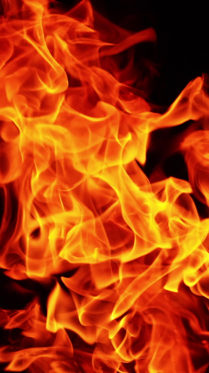 Hot red flame from the bonfire. Upper part of bonfire at black backdrop isolated. Close up. Vertical video