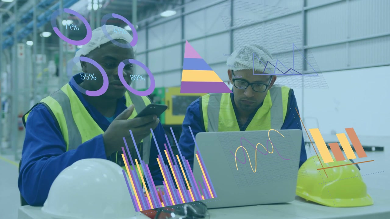 Two male factory workers taking phone call then shifting to laptop, reviewing animated charts