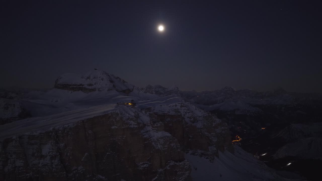La luce lunare illumina l'altopiano innevato sul Sass Pordoi, sopra il Passo Pordoi nelle Dolomiti, Trentino-Alto Adige, Italia - Ripresa orbitale con drone