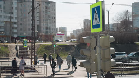 close view of a busy city crosswalk with pedestrians and a traffic light, with individuals crossing the street