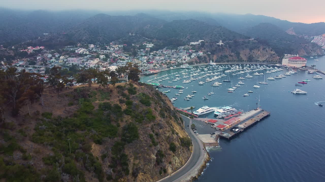vista lateral del dron sobre la terminal de avalon hacia el puerto deportivo, el muelle, la ciudad en la mañana brumosa, la isla catalina