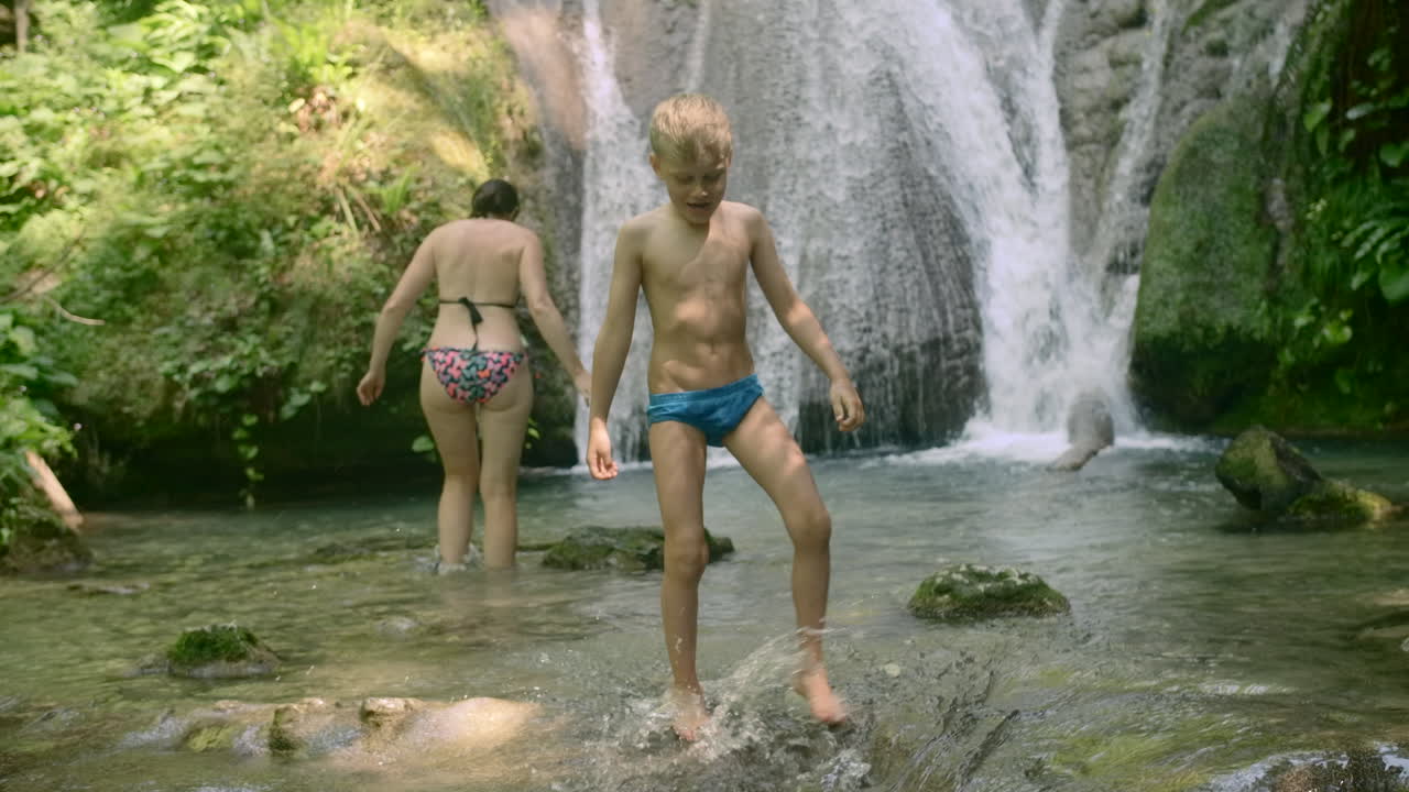 un niño y una mujer disfrutando de una cascada.