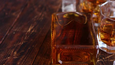 Bottle-of-whiskey-with-two-glasses-placed-on-rustic-wooden-table