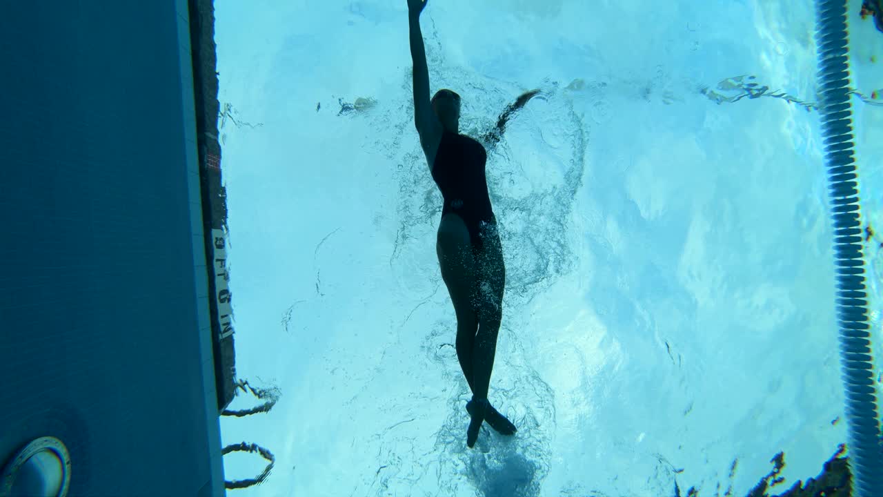 Underwater shot of a female swimming through the lane of a pool using perfect form