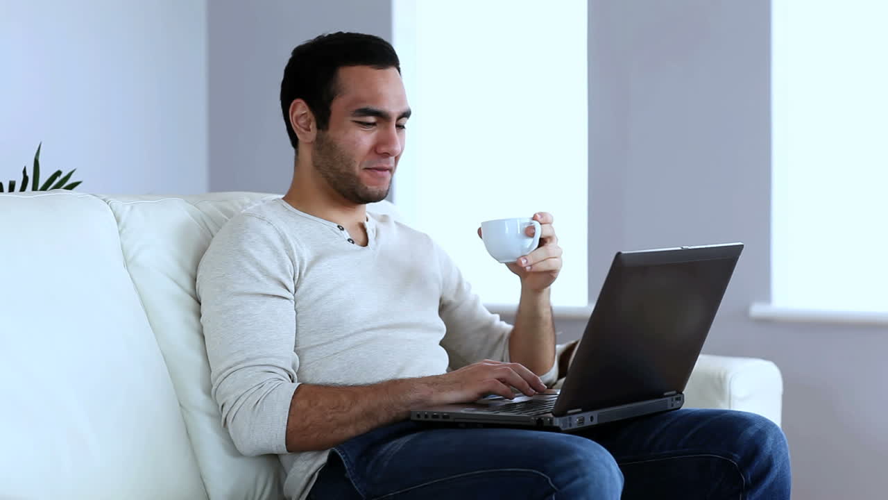 hombre bebiendo un café mientras usa una computadora portátil