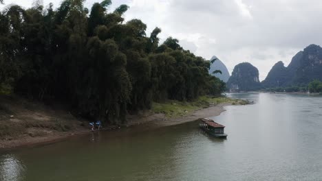 Aerial:-backpackers-hiking-Li-River-karst-mountain-valley,-China