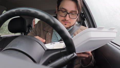 young driver man eating out of a white take away box at driver's seat