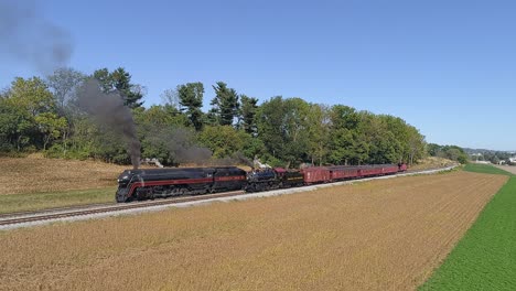 an aerial view of two norfolk and western steam locomotives steaming up on two tracks in the countryside