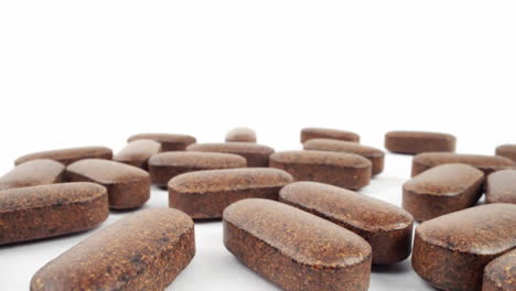 close-up of scattered brown nutritional supplements on white background