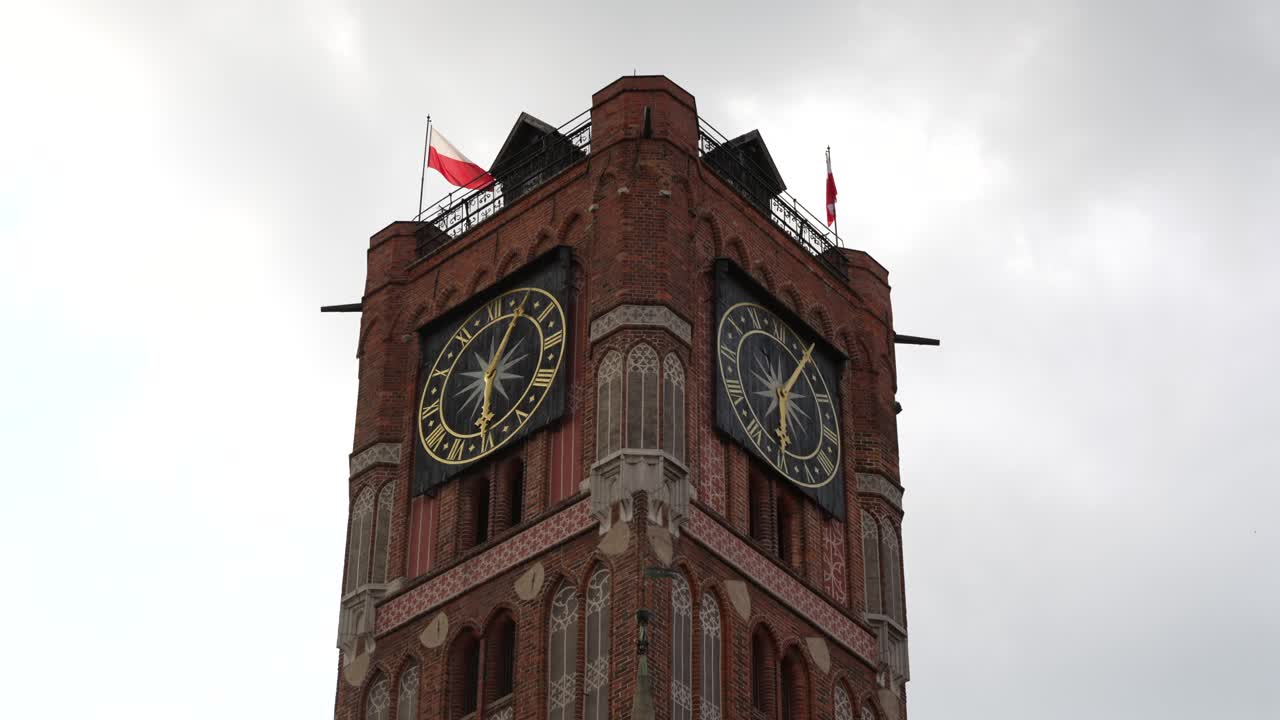 Torun town hall tower in gothic style, with clocks and Polish flag
