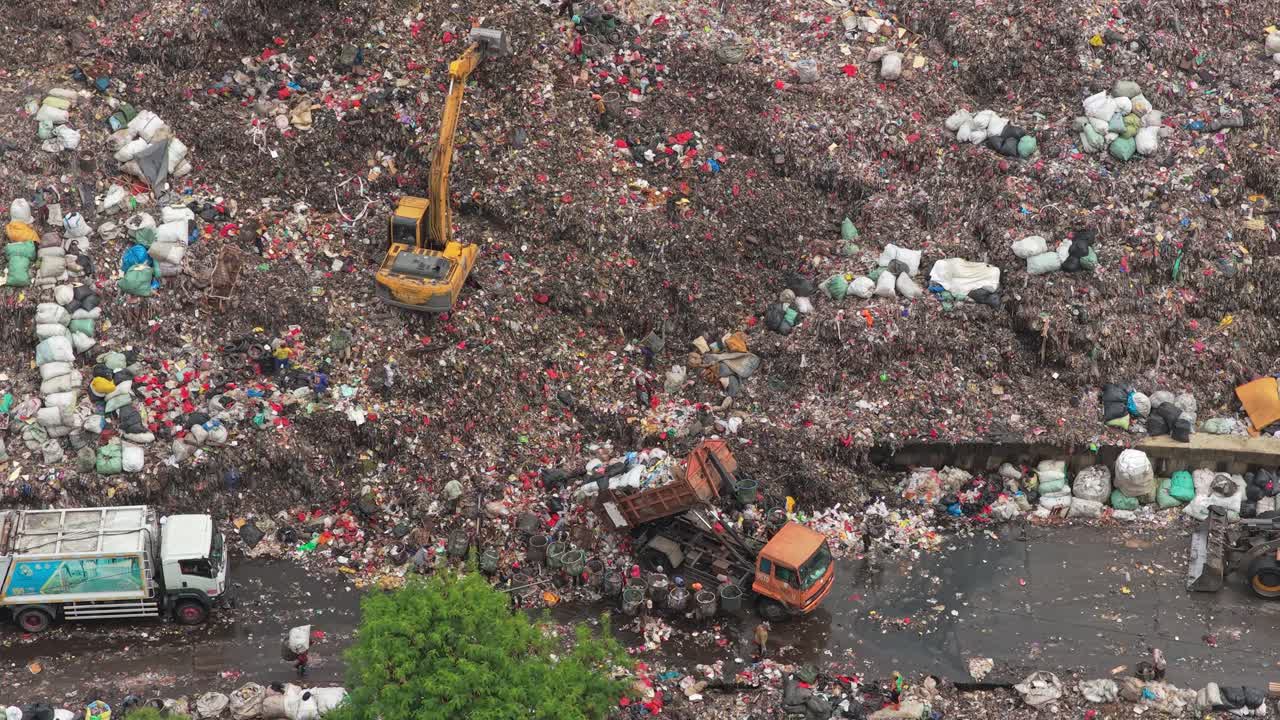 Escavatore al lavoro in un'enorme discarica a Giacarta